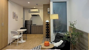 A compact living space with a kitchenette, a dining area, and a seating area with a sofa and a small table. - Corgi House Homestay Nha Trang (Nha Trang)