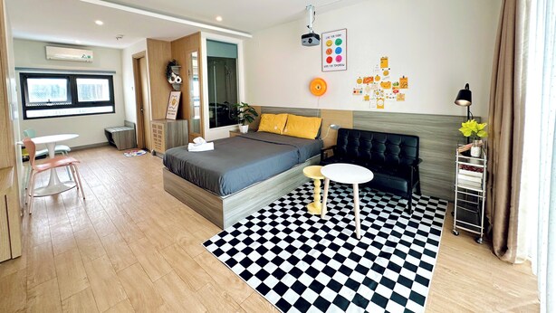 A modern bedroom with a bed, a sofa, a small table, and a checkered floor. - Corgi House Homestay Nha Trang (Nha Trang)