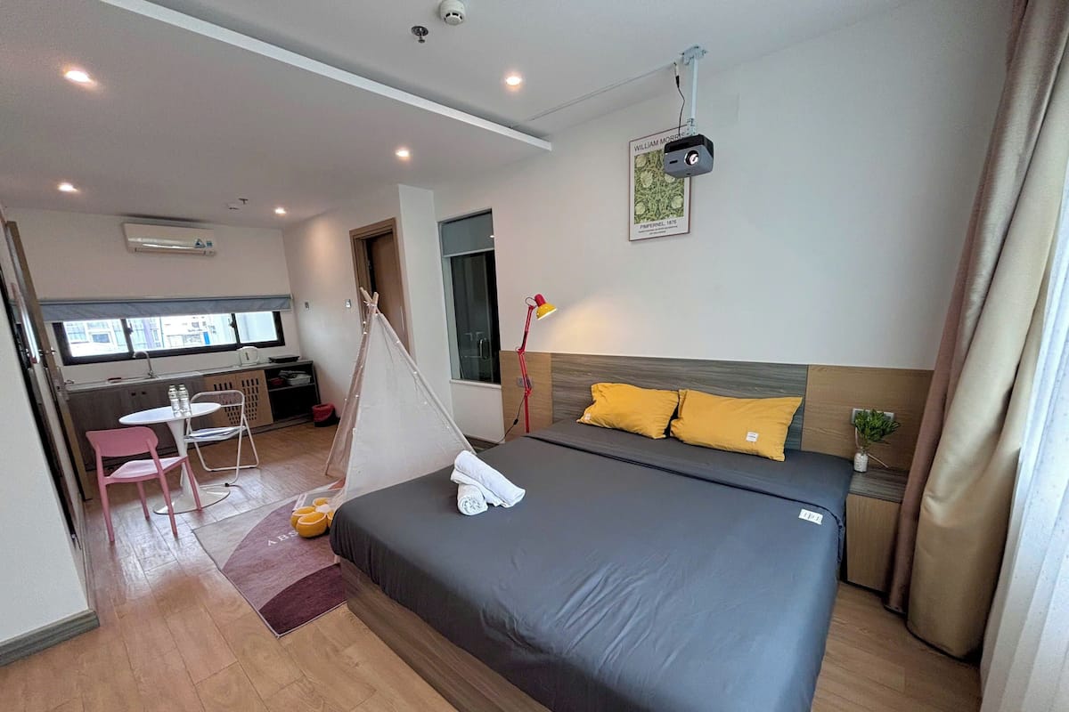 Ein Hotelzimmer mit Bett, Schreibtisch, Stuhl, einem kleinen Tisch und einem Fenster.