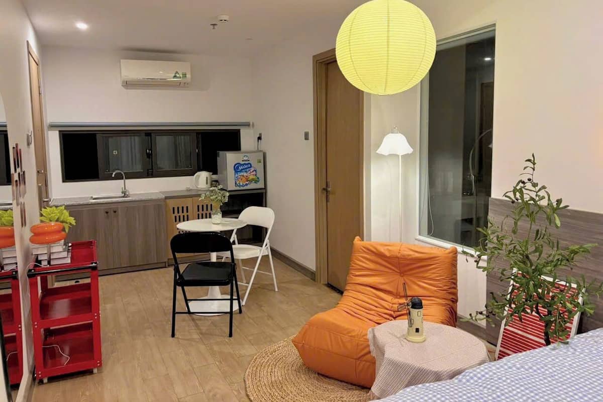 Ein kompakter Wohnraum mit Küchenzeile, Essbereich und einer Sitzecke mit Sofa und kleinem Tisch.