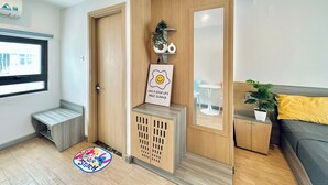 A modern living room with a wooden partition, a sofa, a small table, and a potted plant. - Corgi House Homestay Nha Trang (Nha Trang)