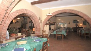 Un restaurant avec des arches en briques, des poutres en bois et des tables dressées pour le repas.