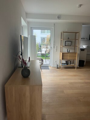 Una sala de estar moderna con una mesa de centro de madera, una estantería y vistas al exterior a través de un ventanal.