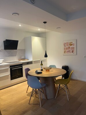 Una cocina moderna con zona de comedor, suelo de madera y un televisor de pantalla plana montado en la pared.