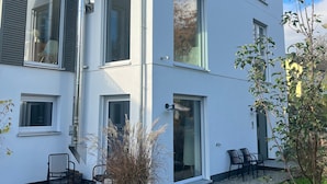 Edifici modern de dos pisos amb grans finestres, un porxo cobert i mobiliari d'exterior.