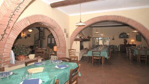 Un espace repas agrémenté d’arches en briques, de poutres en bois et de tables dressées pour le dîner.