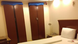 A hotel room with a double bed, a nightstand, a desk, and two wardrobes. - Giggler (Jamnagar)