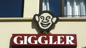 A building with a sign that reads "GIGGLER" and a stylized face graphic above the sign. - Giggler (Jamnagar)