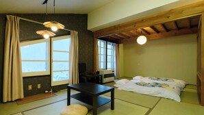 A traditional Japanese room with tatami flooring, a futon bed, a television, and a ceiling fan. - HOTEL ST.MORITZ (Yuzawa)