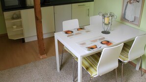 A dining area with a white table, chairs, a candle holder, and a framed picture on the wall.