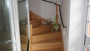 A wooden staircase with a glass door at the top, a small table with decorative items, and a wall-mounted telephone.