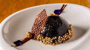 A dessert on a white plate with a lattice structure and nuts around it.