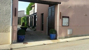 The entrance to La Musarde with a clear archway, potted plants, and a visible sign.