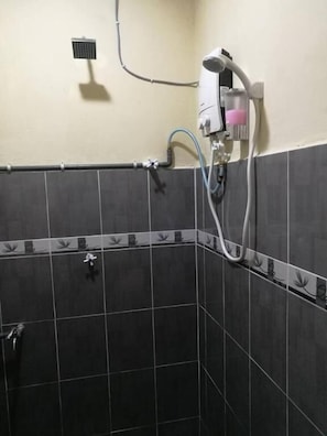 A bathroom with dark tiled walls, a shower area, and a hand dryer mounted on the wall. - Tambun D'Mewah homestay (Ipoh)