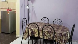 A dining area with a table set for four, surrounded by chairs, a clock on the wall, and a painting of red flowers. - Tambun D'Mewah homestay (Ipoh)