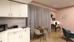 A modern kitchen with white cabinets, a microwave, and a dining area with a table, chairs, and a clock on the wall. - 1 BR Apt TLV TAU by Sea N' Rent (Tel Aviv)
