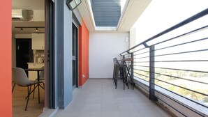 A balcony with a metal railing, a table with chairs, and a view of the city. - 1 BR Apt TLV TAU by Sea N' Rent (Tel Aviv)