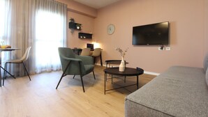 A living room with a sofa, a chair, a coffee table, a TV, and a clock on the wall. - 1 BR Apt TLV TAU by Sea N' Rent (Tel Aviv)