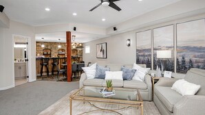 A spacious living room with a modern sofa, a glass coffee table, and a view of a kitchen and dining area. - Escape to Modern Mountain Retreat Near Top Ski Resorts w/ Hot Tub! (Gypsum)