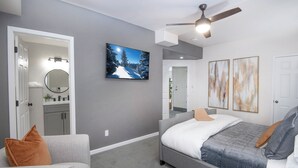 A modern bedroom with a gray sofa, a gray bed, a ceiling fan, and a painting of a snowy landscape. - Escape to Modern Mountain Retreat Near Top Ski Resorts w/ Hot Tub! (Gypsum)