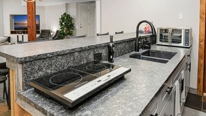 A modern kitchen with granite countertops, a built-in stove, a sink, and a microwave. - Escape to Modern Mountain Retreat Near Top Ski Resorts w/ Hot Tub! (Gypsum)