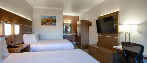 A hotel room with two beds, a desk, a chair, a TV, and a painting on the wall.