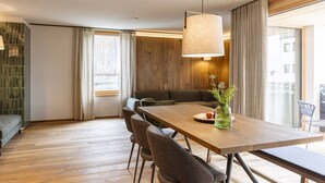 Un espace repas moderne avec une table en bois, des chaises à revêtement gris et un luminaire suspendu.