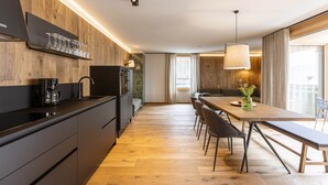 Une cuisine moderne avec un revêtement mural en bois, une machine à café et un coin repas comprenant un banc et des chaises.