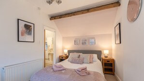 Une chambre à coucher avec un lit, deux tables de chevet, une horloge murale et un tableau encadré.