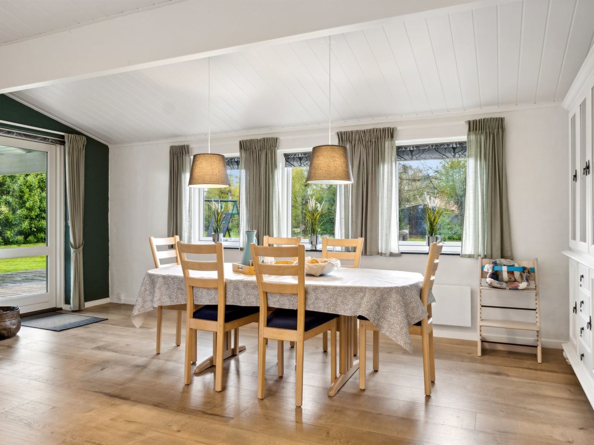 Ein Essbereich mit einem runden Tisch, sechs Holzstühlen und zwei Pendelleuchten.