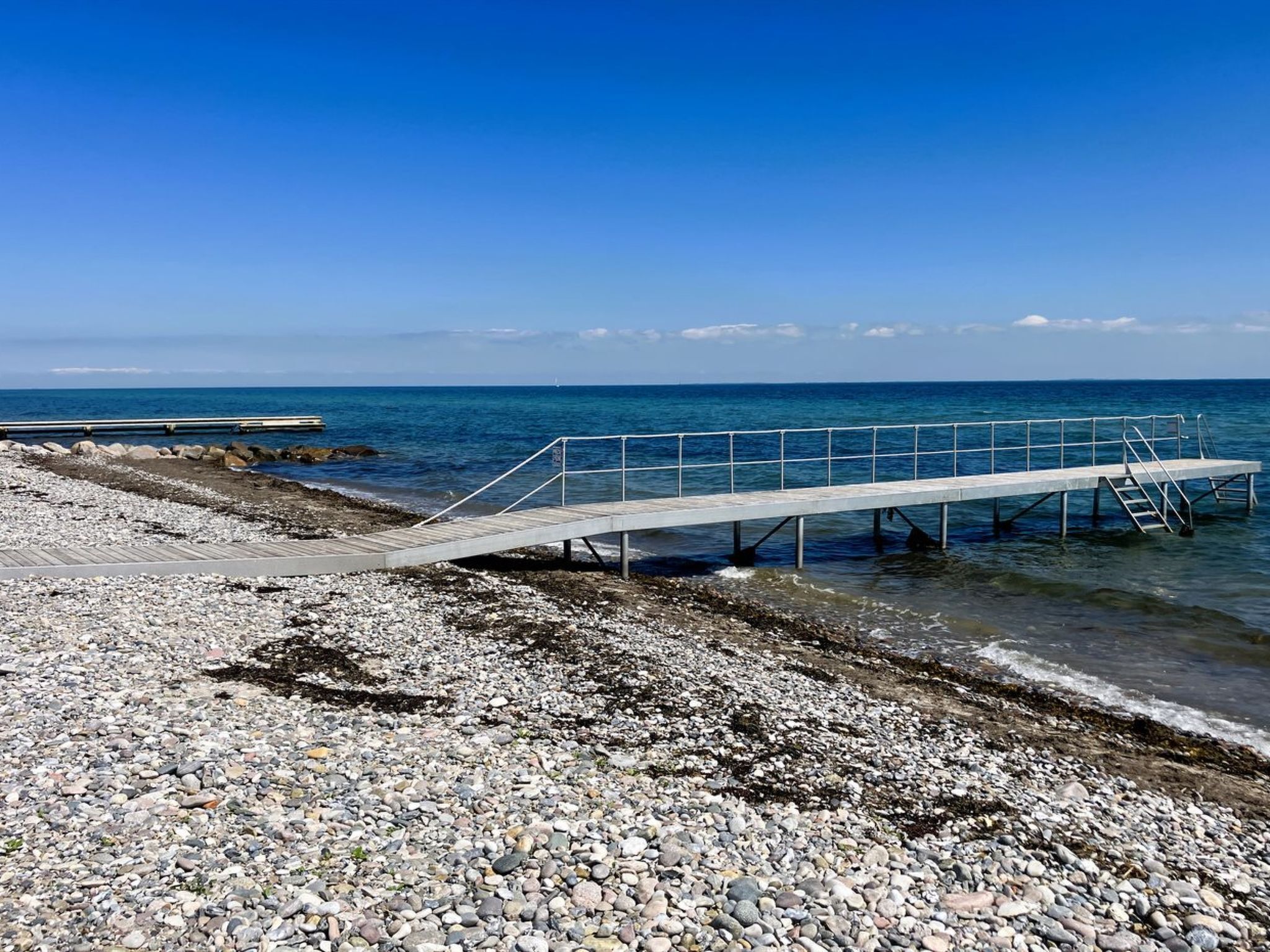 A pier extending into the sea with a rocky shoreline.