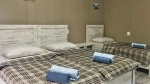 A hotel room with two beds, each with a plaid bedspread and pillows. There are two small pictures on the walls. - Spacious 4-bedroom house in charming Kutaisi with WiFi, AC (Kutaisi)