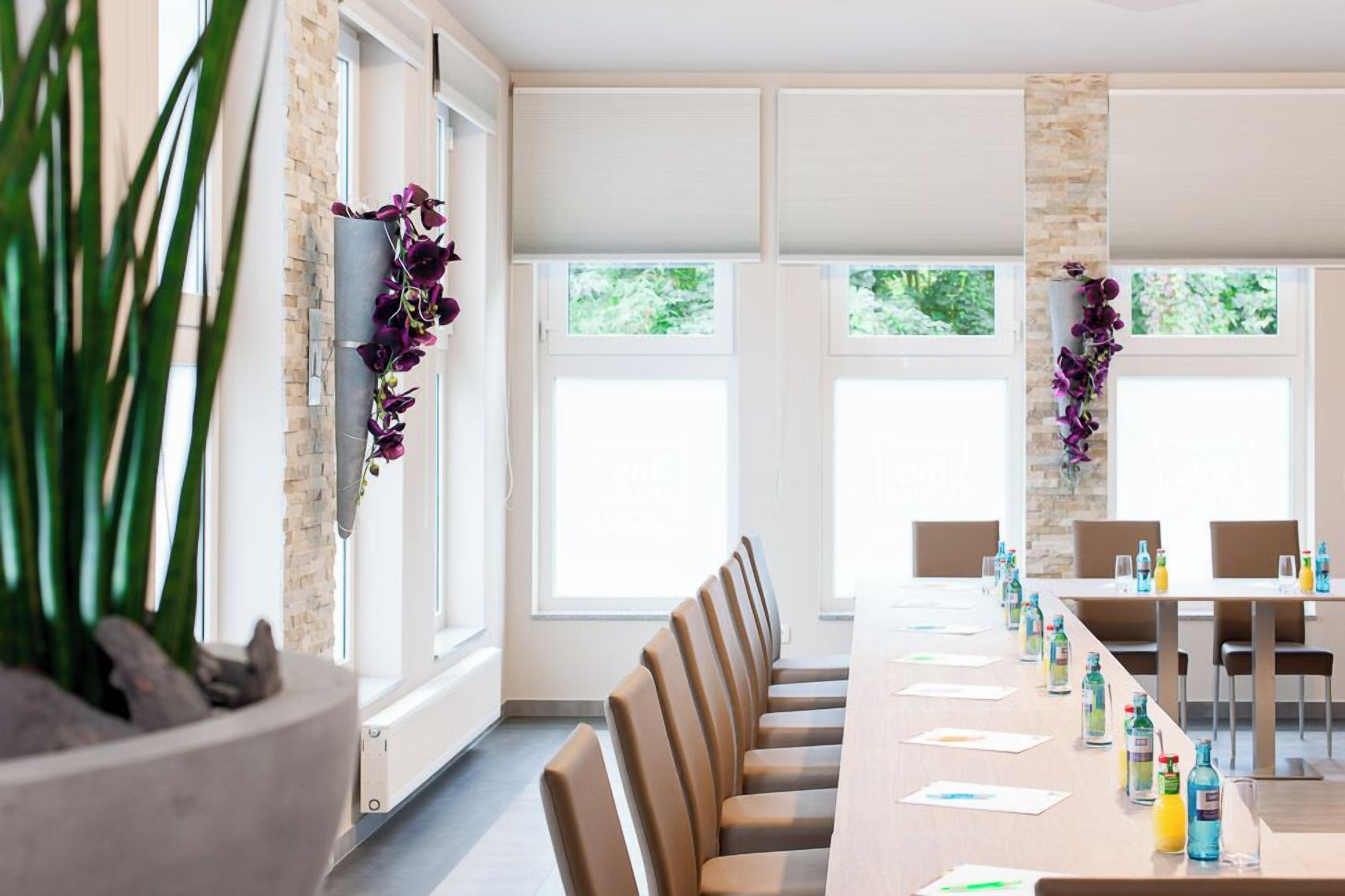 A conference room with a long table, chairs, and a potted plant.