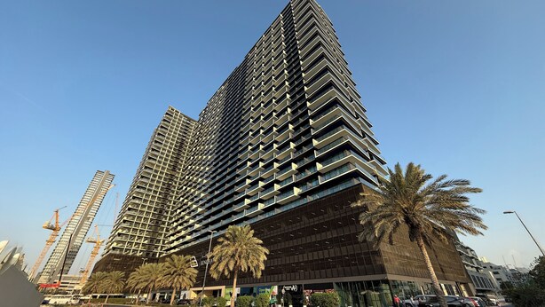 A modern high-rise building with a unique angular design, featuring multiple balconies and large windows. - Bright 1BR in Binghatti Corner (Dubai)