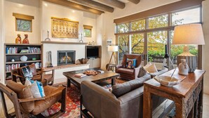 A cozy living room with a fireplace, leather furniture, and large windows.