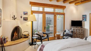 A cozy room with a fireplace, a bed, a TV, and a large window with a view of the outdoors.