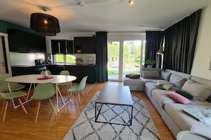 A modern living room with a dining area, a sofa, and a kitchen. - Luxury apartment with stunning mountain view (Ebene Reichenau)