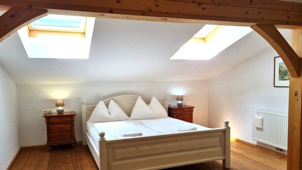 A bedroom with a skylight, a bed, two bedside tables, and a radiator. - Wonderful apartment with views of the slopes (Bad Kleinkirchheim)