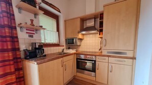 A compact kitchen with wooden cabinets, a microwave, an oven, and a coffee maker. - modern apartment with panoramic views (Bad Kleinkirchheim)