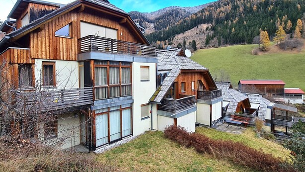 A modern chalet with a wooden exterior, large windows, and a balcony. It is situated in a mountainous area with a view of the surrounding landscape. - modern apartment with panoramic views (Bad Kleinkirchheim)