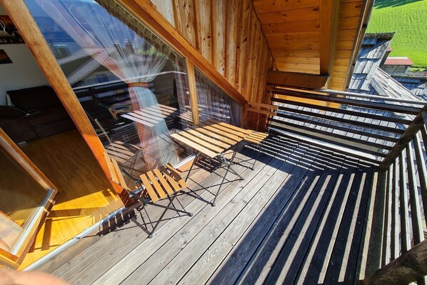 A wooden deck with a table and chairs, a glass door, and a view of a green landscape. - modern apartment with panoramic views (Bad Kleinkirchheim)