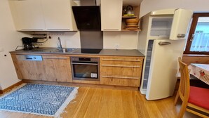 Een compacte keuken met een vaatwasser, oven en een witte koelkast.