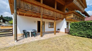 Un chalé de madera con balcón, mobiliario exterior y un jardín cuidado.