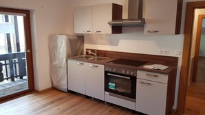 A compact kitchen with a built-in oven, a stainless steel sink, and a wooden countertop.