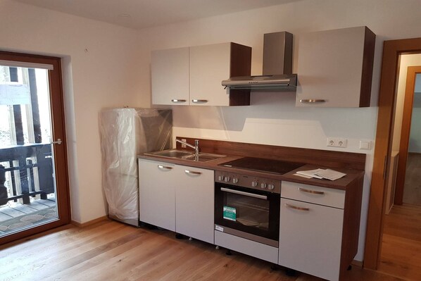 A compact kitchen with a built-in oven, a stainless steel sink, and a wooden countertop.