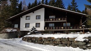 A multi-story chalet with a stone foundation, wooden balconies, and a snow-covered roof. - Nature & Ski Retreat in Bad Kleinkirchheim (Bad Kleinkirchheim)