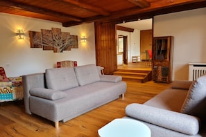 Un salon avec un canapé gris, un plancher en bois et un escalier menant à une autre pièce.