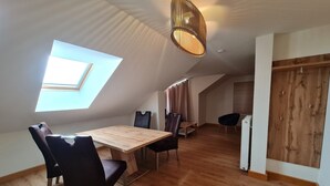 A modern loft bedroom with a skylight, wooden flooring, a dining area with a table and chairs, and a built-in wardrobe. - Apartment in Bad Kleinkirchheim near hiking (Bad Kleinkirchheim)