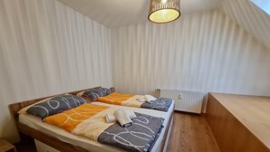 A bedroom with a wooden bed, white curtains, and a radiator. - Apartment in Bad Kleinkirchheim near hiking (Bad Kleinkirchheim)