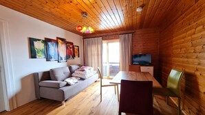 A cozy cabin interior with a wooden ceiling, a sofa, a dining table, and a TV. - Pet-friendly apartment in Bad Kleinkirchheim (Bad Kleinkirchheim)